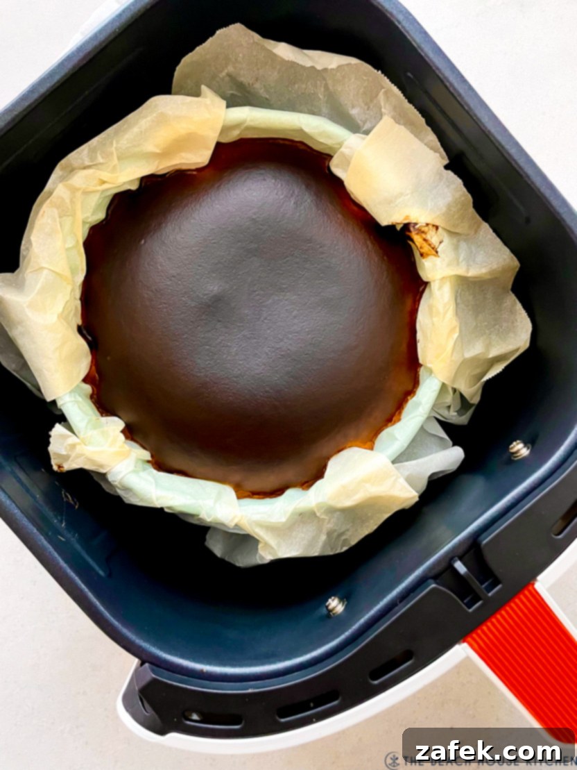 Perfect Air Fryer Basque Cheesecake 3 An overhead shot of a freshly baked Air Fryer Basque cheesecake cooling within the air fryer basket, showcasing its distinctive dark, caramelized crust.
