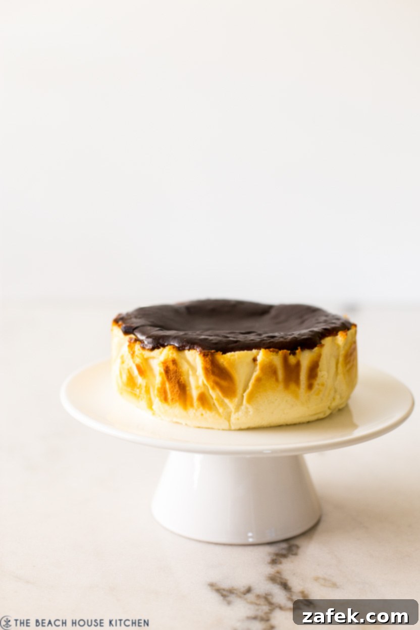 Perfect Air Fryer Basque Cheesecake 5 An intimate close-up shot of a perfectly 'burnt' Air Fryer Basque cheesecake on a white cake pedestal, highlighting its deeply caramelized top and luscious, creamy texture.