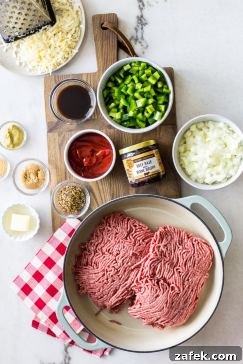 Overhead shot showcasing all the fresh, vibrant ingredients laid out for making Philly Cheesesteak Sloppy Joes, including ground beef, vegetables, cheese, and Zoup! Beef Base