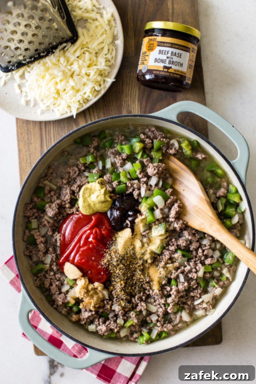 Overhead photo of cooked hamburger meat mixed with ketchup and spices in a skillet, showcasing the rich, savory sauce before the addition of cheese