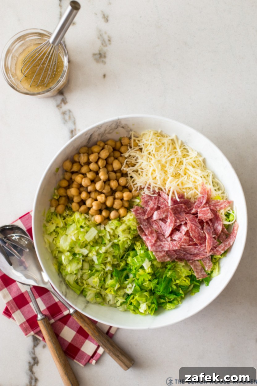 Overhead shot of the pre-mixed chopped salad ingredients in a bowl before dressing, showing the colorful blend of greens, chickpeas, salami, and mozzarella