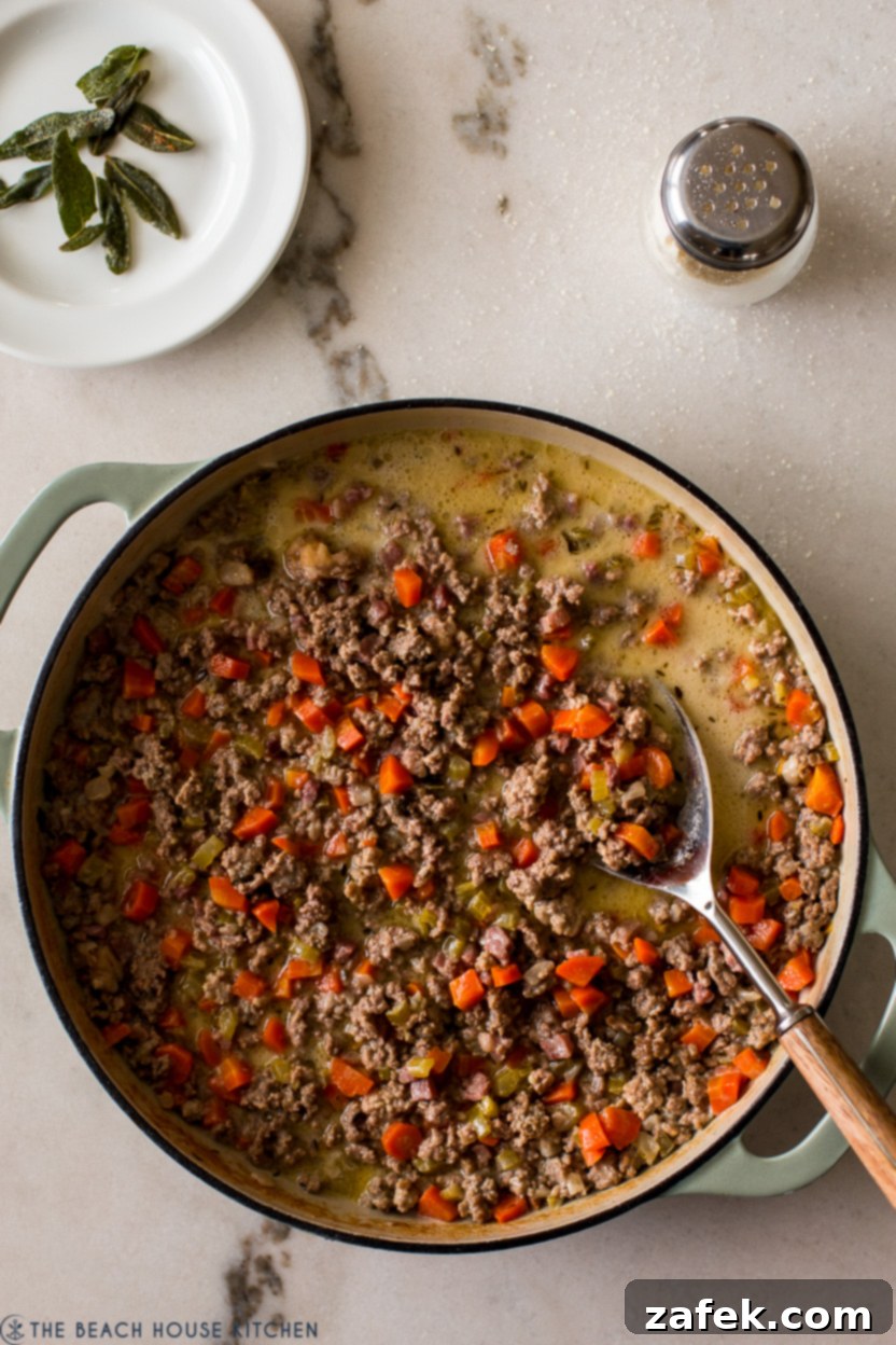 Bianco Bolognese 3 A close-up overhead shot of creamy White Bolognese simmering gently in a large skillet, rich with finely browned meat and vegetables, ready to be tossed with pasta.