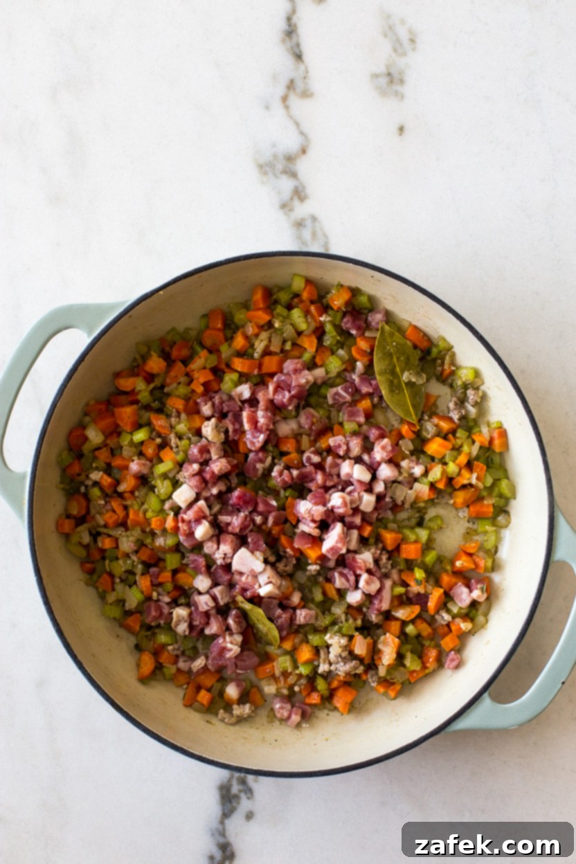 Bianco Bolognese 7 An overhead view of a skillet filled with a fragrant mixture of sautéed vegetables and perfectly rendered, crispy pancetta, forming the savory base of the Bolognese.
