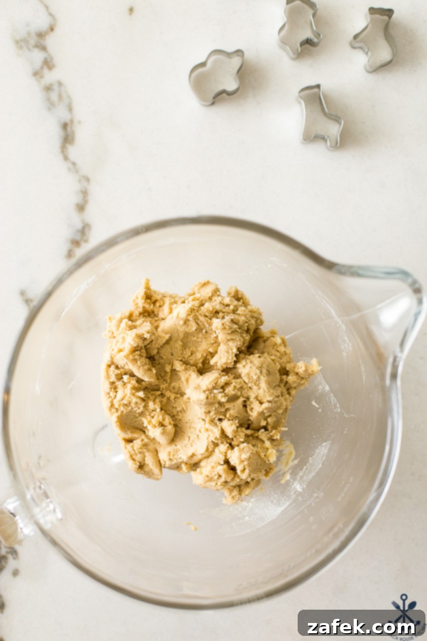 Overhead photo of glass bowl of cookie dough with cookie cutters off to the side