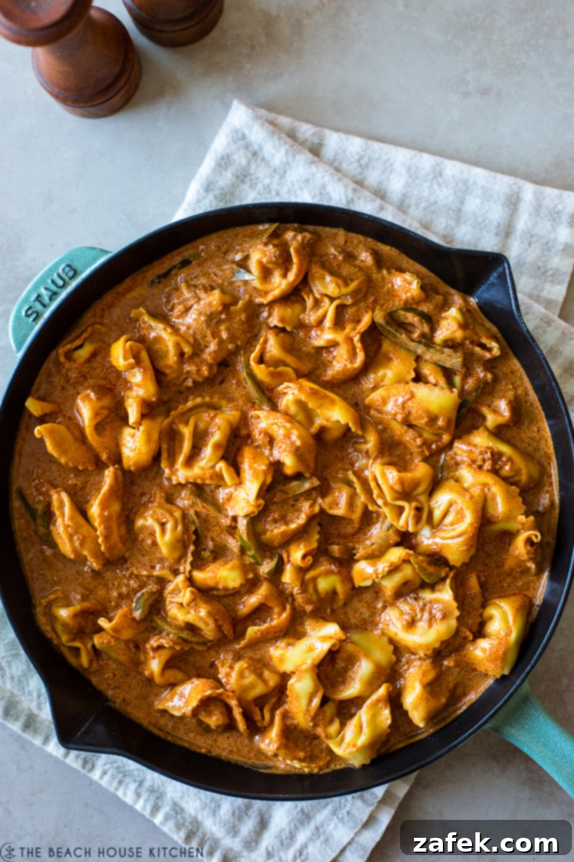 Up close overhead photo of a skillet of chicken tortellini paprikash, garnished with fresh parsley, highlighting the creamy, red sauce and plump pasta.