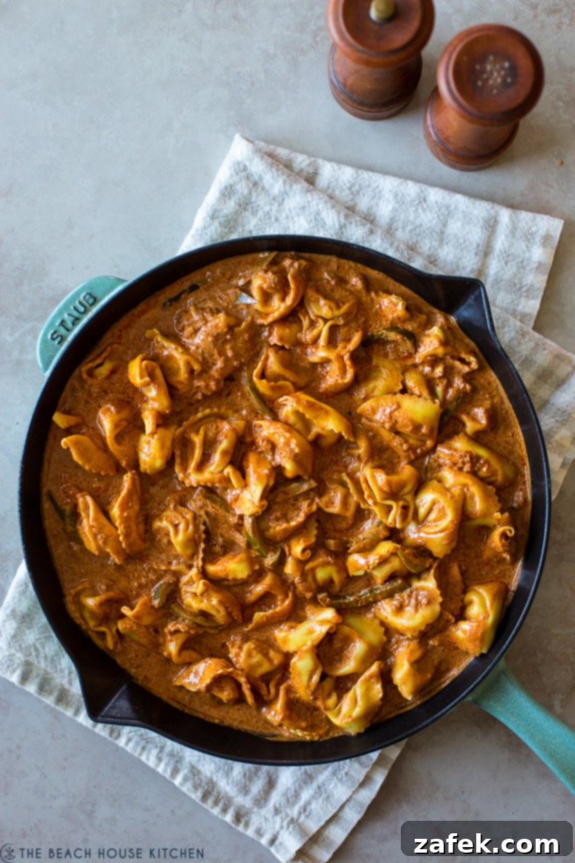 Overhead photo of a skillet filled with golden chicken tortellini coated in a rich, vibrant paprikash sauce, ready to be served.