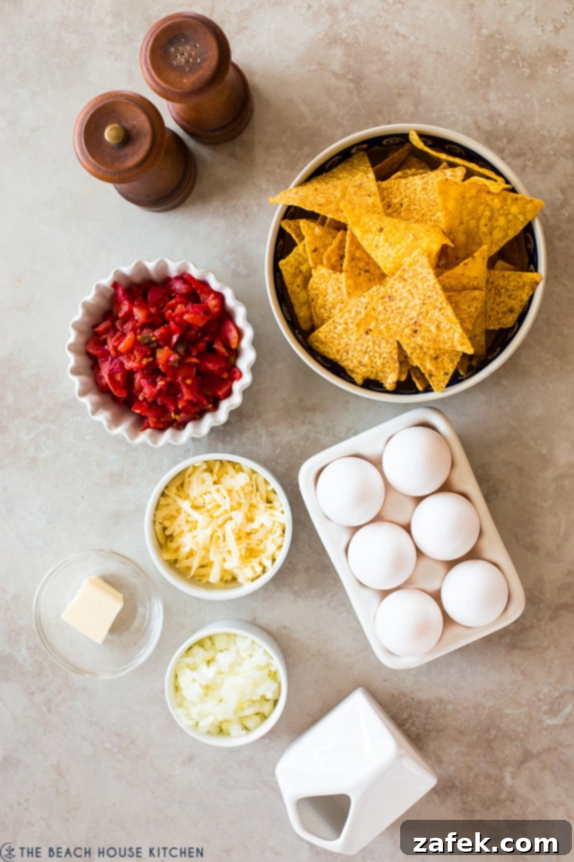Overhead photo displaying a meticulously arranged selection of fresh ingredients for an egg-based dish, including whole eggs, a bowl of tortilla chips, chopped onions, a block of cheese, and a can of Rotel, all on a wooden surface.