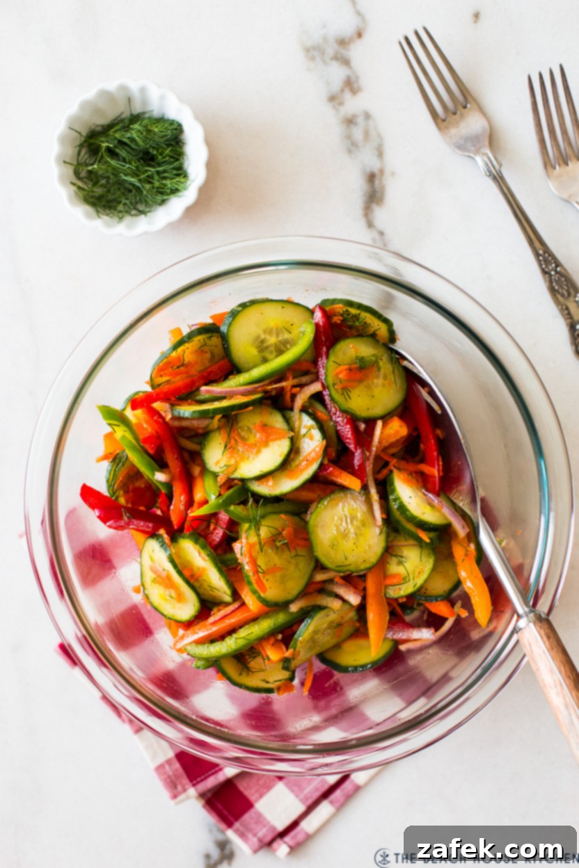 Overhead photo of a vibrant Easy Cucumber Salad in a serving bowl, showcasing crisp cucumbers, colorful bell peppers, and fresh dill.