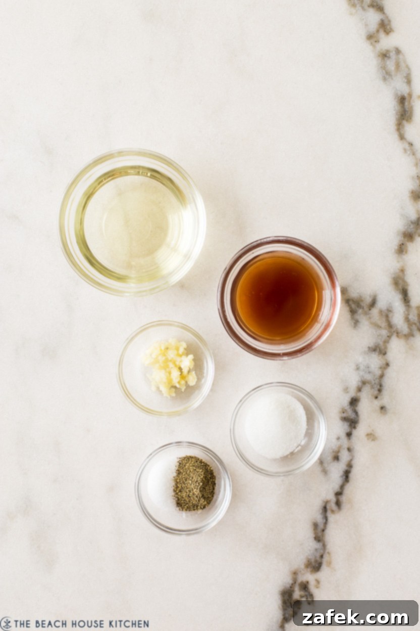 Overhead photo showing ingredients for the vinaigrette dressing: olive oil, red wine vinegar, garlic cloves, granulated sugar, salt, and pepper.