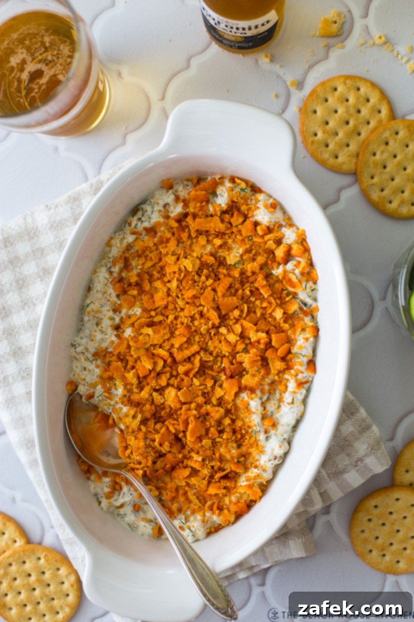 Creamy Dill Pickle Dip topped with crushed Cheez-Its in a white baking dish.
