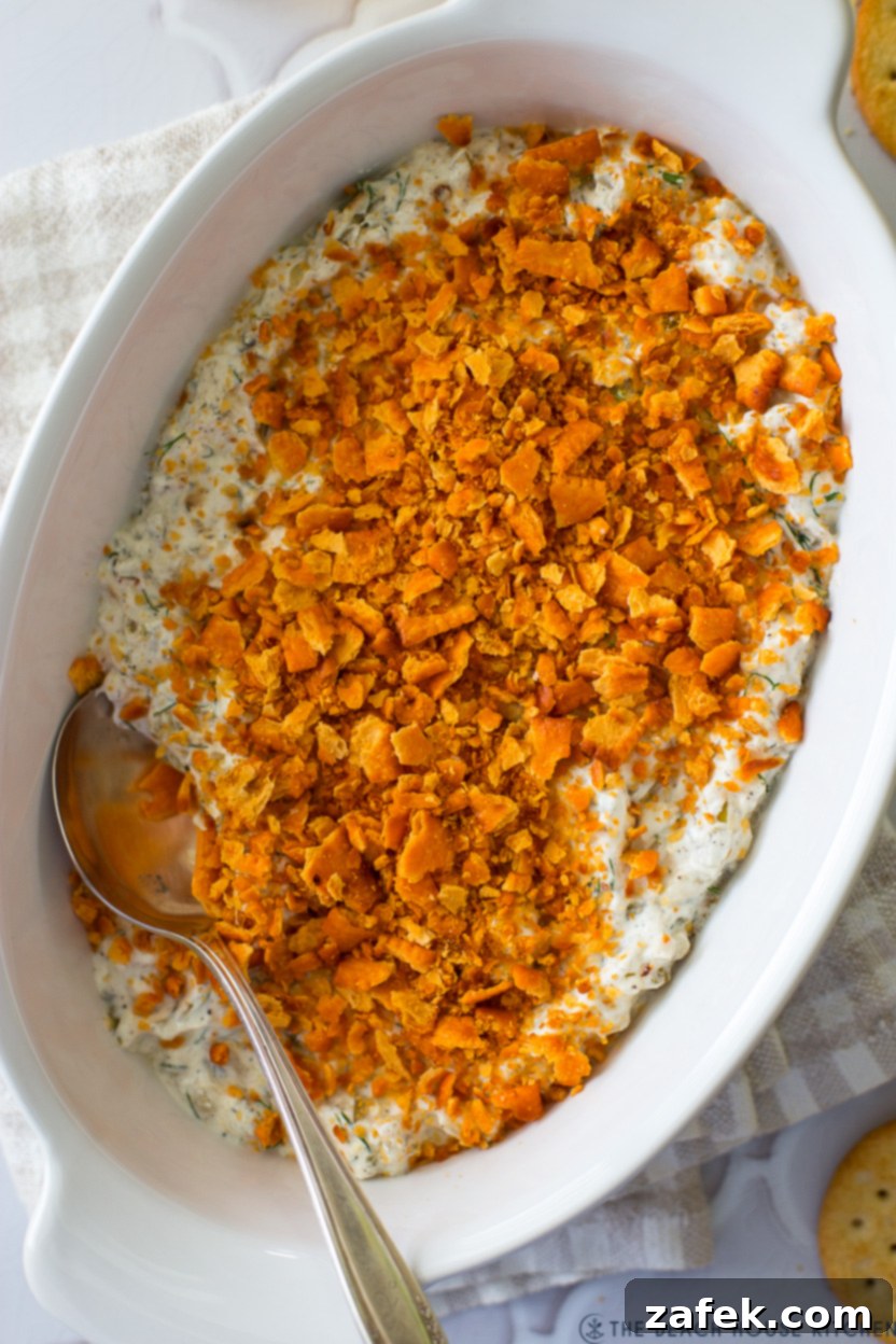 Dill Pickle Dip served warm in a baking dish with crackers and cucumber spears.