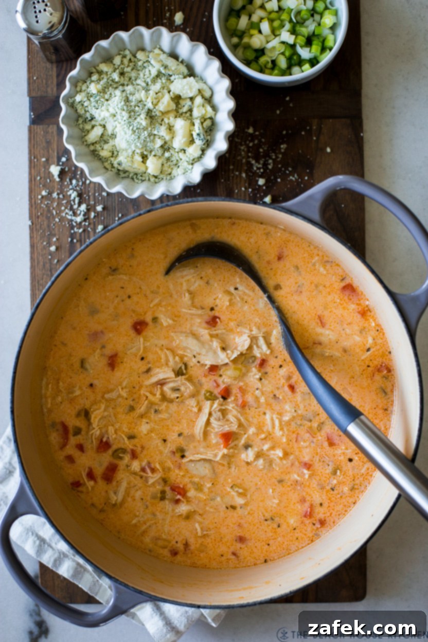 Hot Wing Soup 2 A steaming bowl of vibrant Buffalo Chicken Soup, garnished with fresh blue cheese crumbles and green scallions, hints at the spicy and creamy delight within.