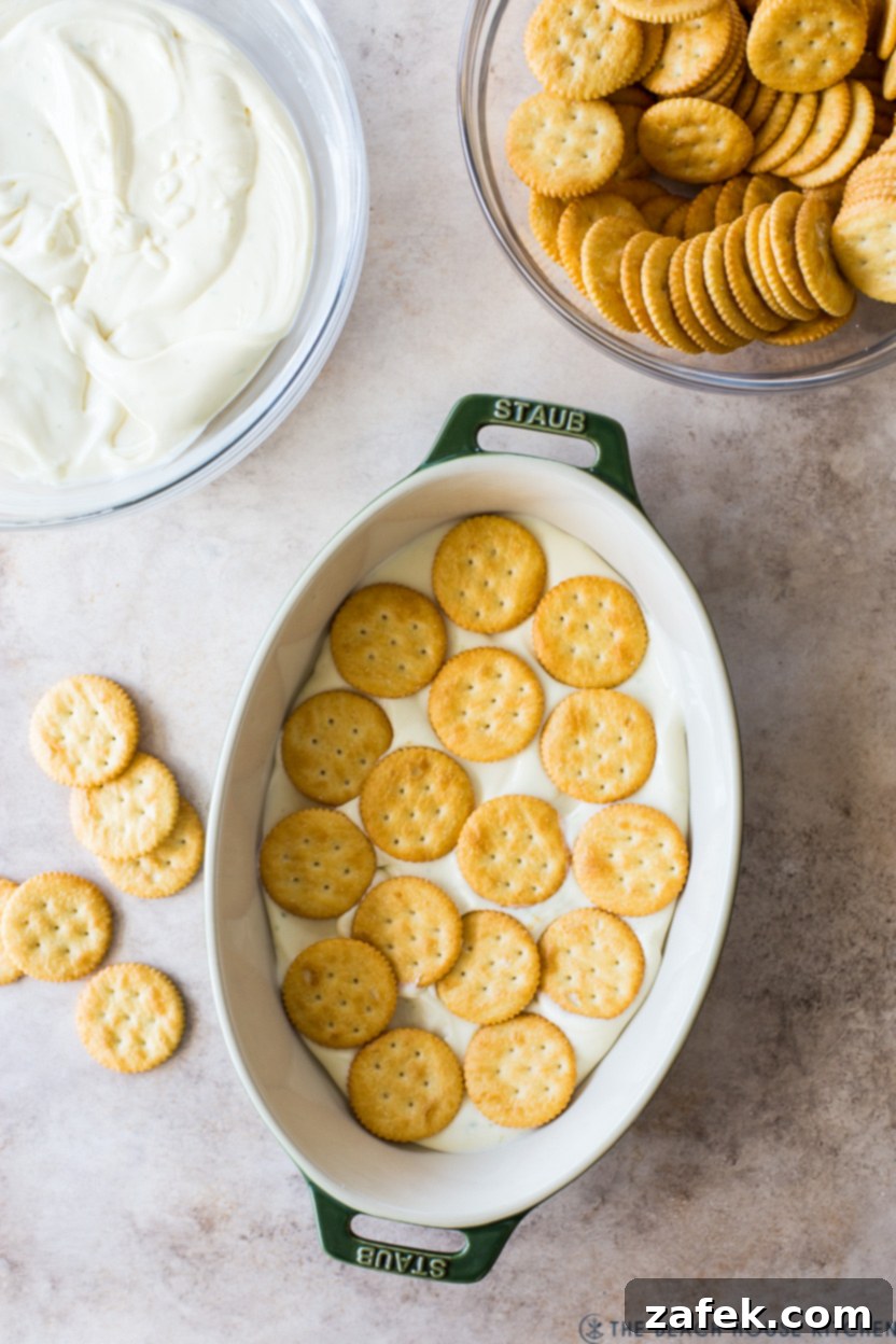 Overhead photo of a Ritz cracker dessert in an oval dish, showing the layered structure before chilling