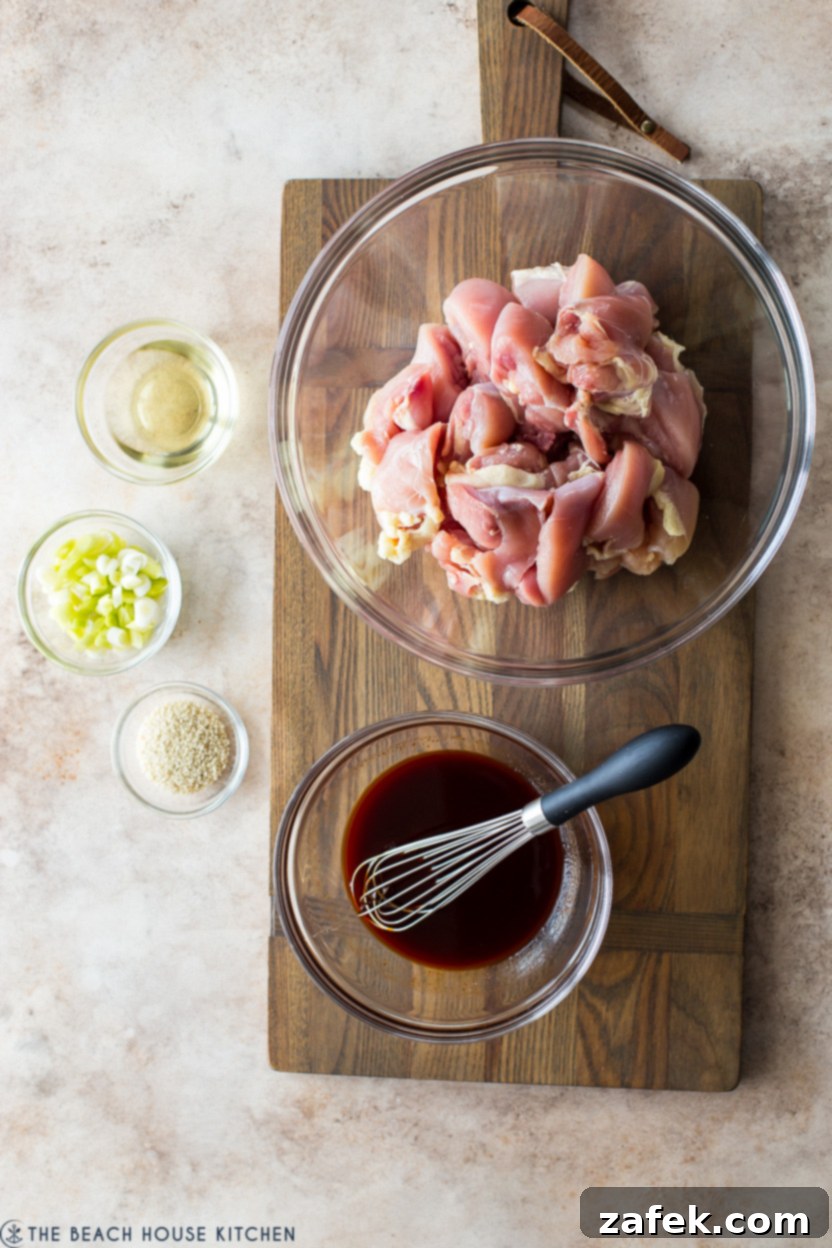 Crispy Gochujang Chicken Stir-Fry 5 Overhead photo of pre-cooked chicken in a bowl with small bowls of minced garlic, chopped ginger, and a dark gochujang sauce mixture ready for cooking.