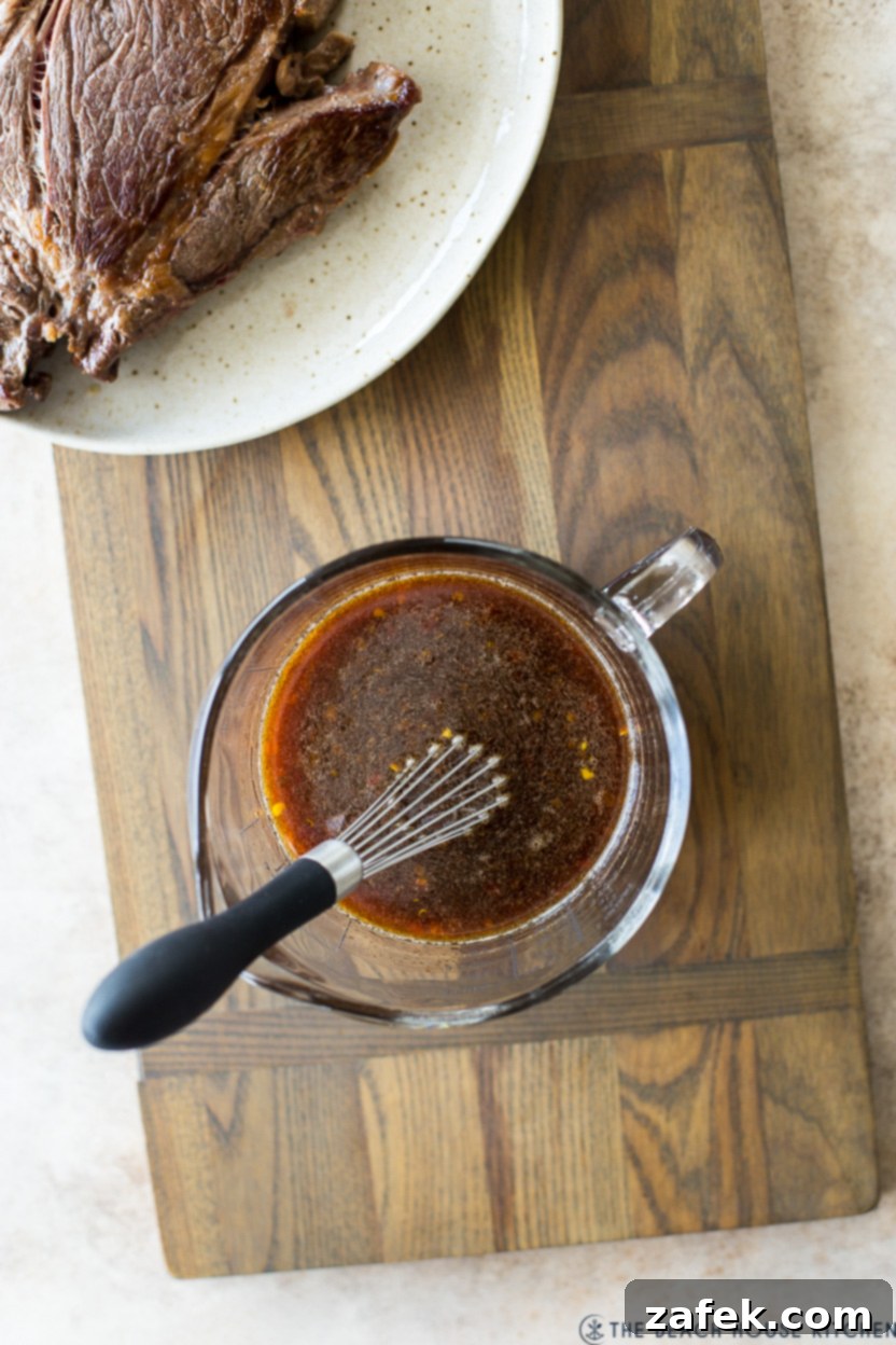 Overhead photo of sauce in a measuring cup with a whisk for pot roast