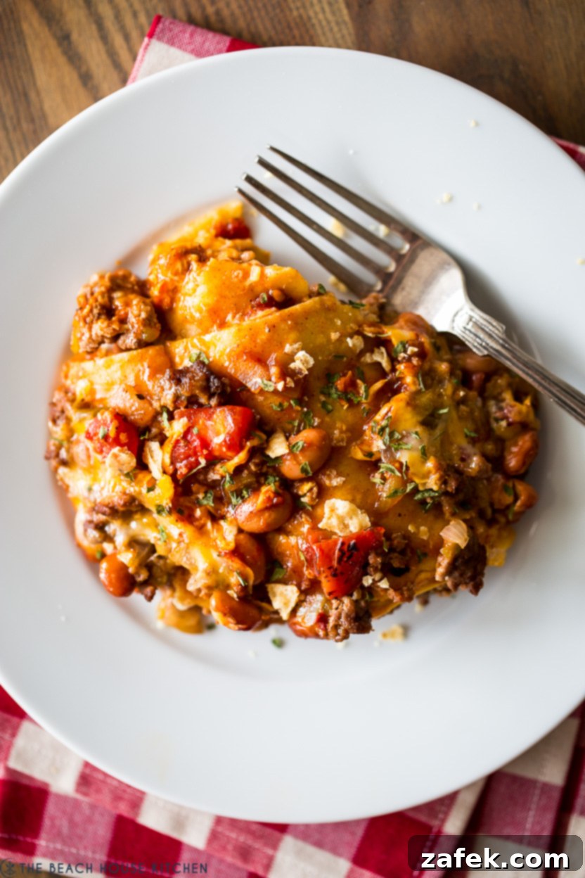 Up close overhead photo of an enchilada casserole in a white bowl with a fork