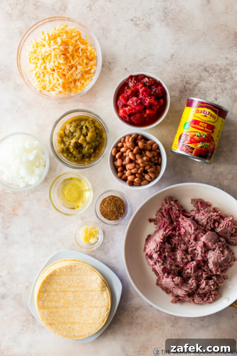 Overhead photo of ingredients for a beef enchilada casserole including ground beef, onions, spices, beans, tomatoes, and tortillas