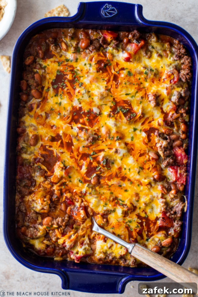 Up close overhead photo of a beef enchilada casserole in a blue baking dish, ready to be served