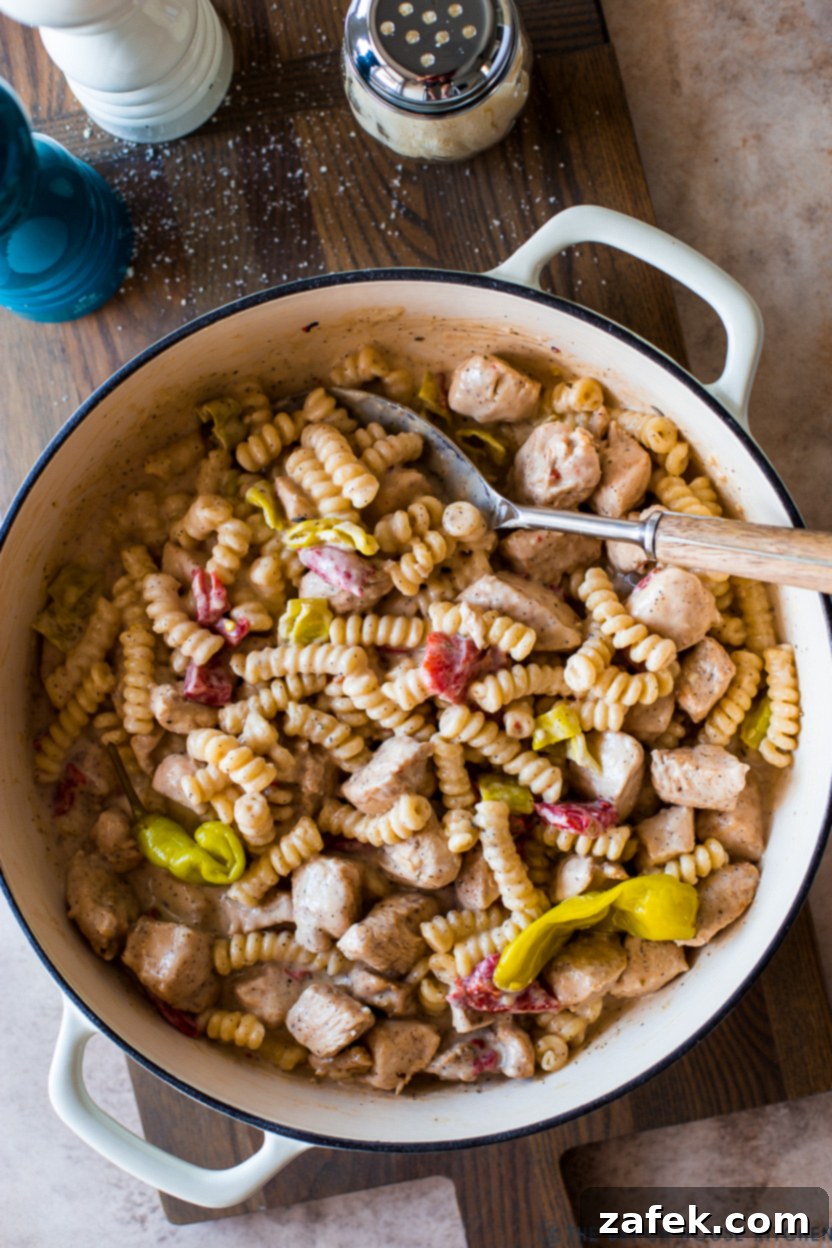 Overhead up close photo of a skillet of Pepperoncini Chicken Pasta, showcasing the creamy sauce, chicken pieces, and vibrant peppers