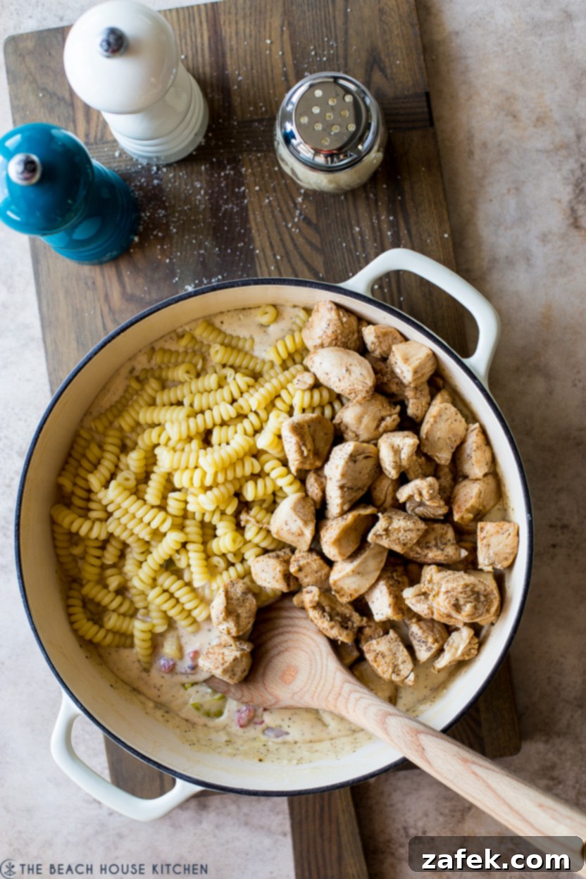 Overhead photo of a skillet dish filled with sauce, pasta and chicken pieces, garnished with fresh herbs