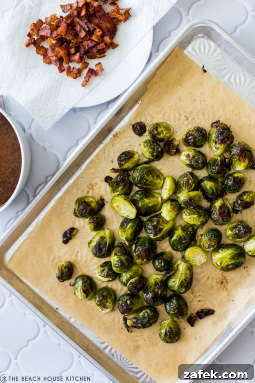 Overhead photo of a serving tray displaying roasted Brussels sprouts alongside a small plate of crispy, chopped bacon, ready to be combined.