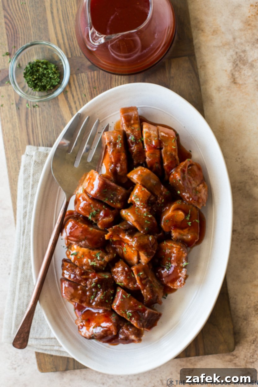 Overhead photo of an oval plate of pork tenderloin slices, garnished with parsley and ready to eat.