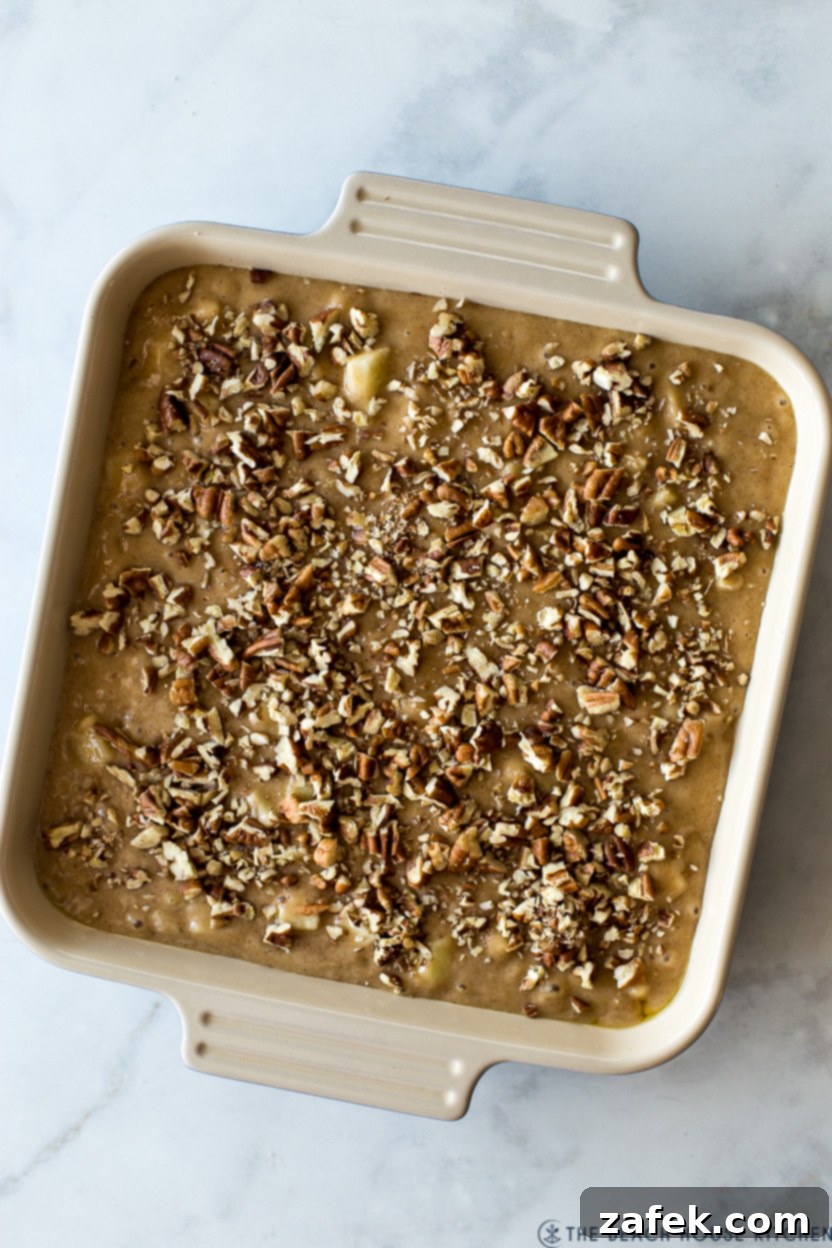 Overhead photo of a baked apple cake, golden brown and perfectly risen, topped with toasted pecans.