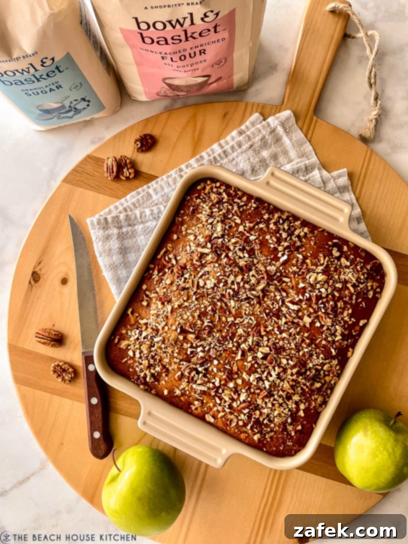 Overhead photo of an apple spice snack cake on a rustic round wooden board, ready to be served