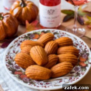 Autumn Spiced Pumpkin Madeleines 11 A beautifully presented Pumpkin Madeleine with a golden hump, garnished with a sprinkle of powdered sugar, placed on a white background.