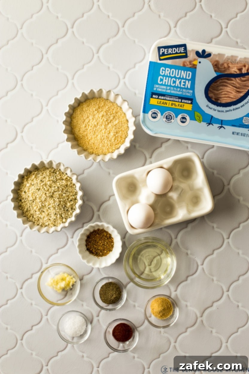 A vibrant overhead shot displaying all the fresh, simple ingredients laid out for homemade chicken meatballs, including ground chicken, eggs, garlic, and various seasonings.