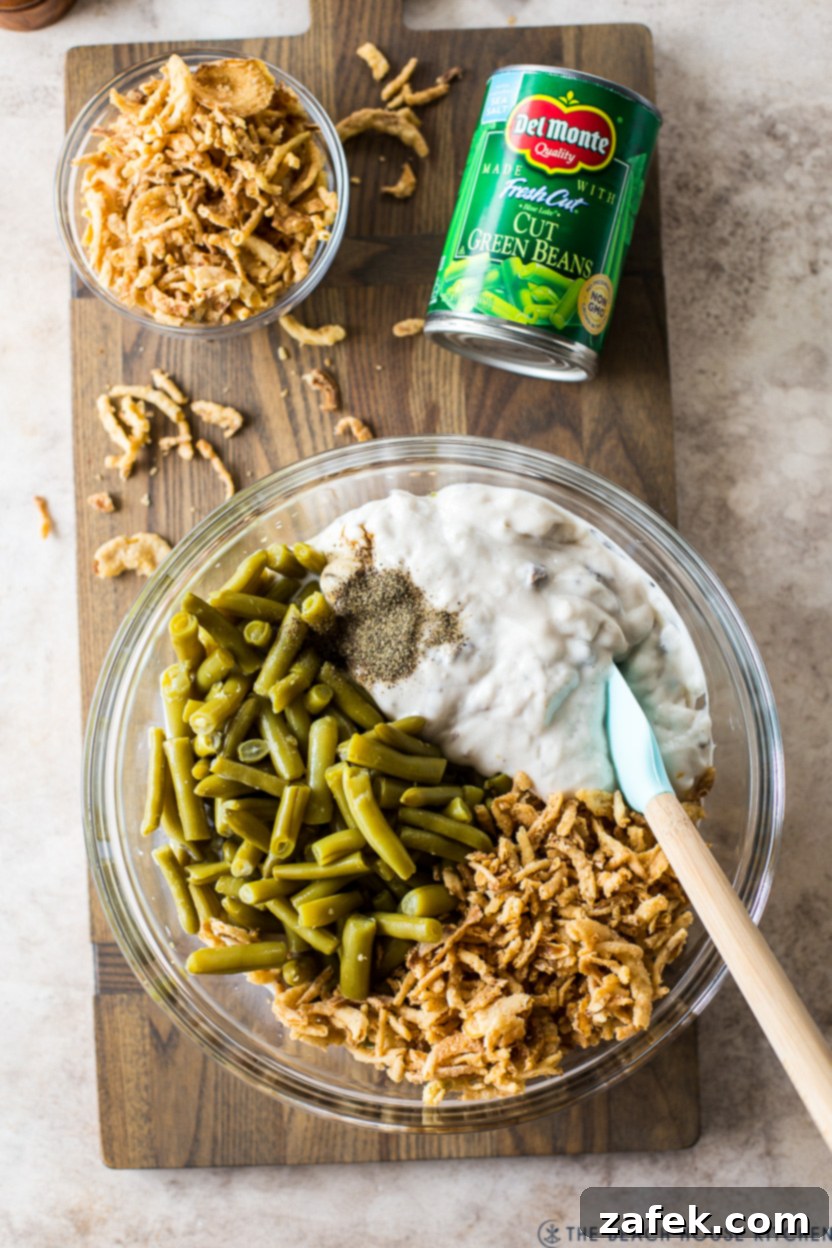 Overhead photo of a bowl filled with ingredients for a green bean side dish, ready for baking
