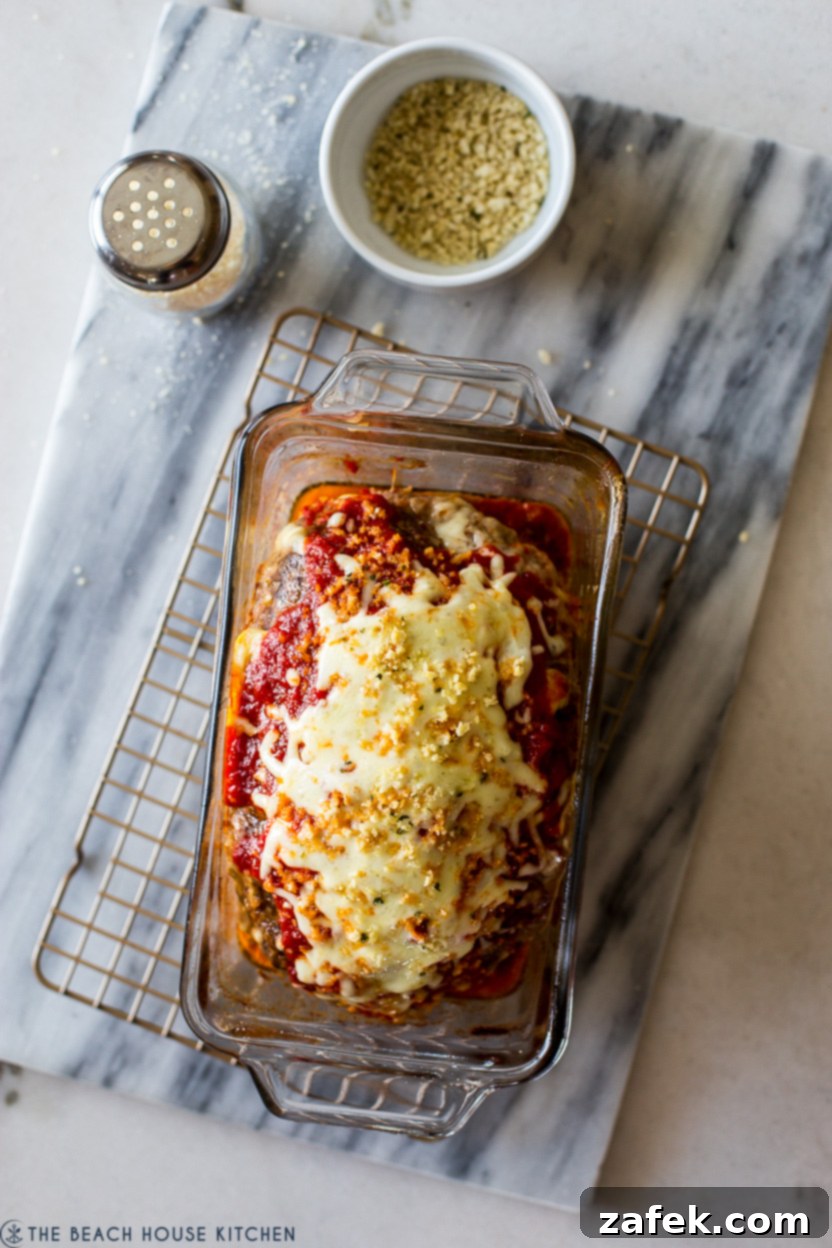 Overhead photo of a freshly baked Italian meatloaf still in its loaf pan, perfectly browned and topped with melted cheese.