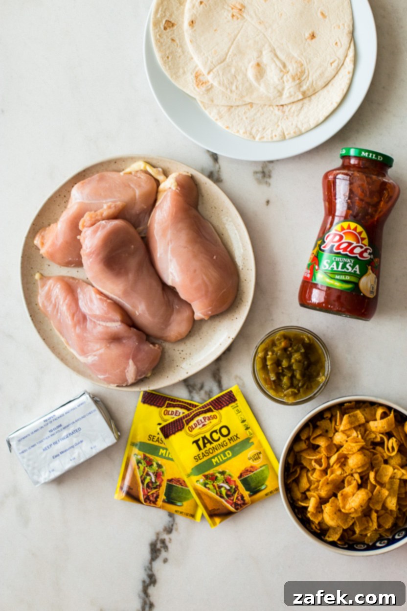Overhead photo of fresh ingredients for slow cooker creamy taco chicken, including chicken breasts, salsa, taco seasoning, green chiles, and cream cheese.