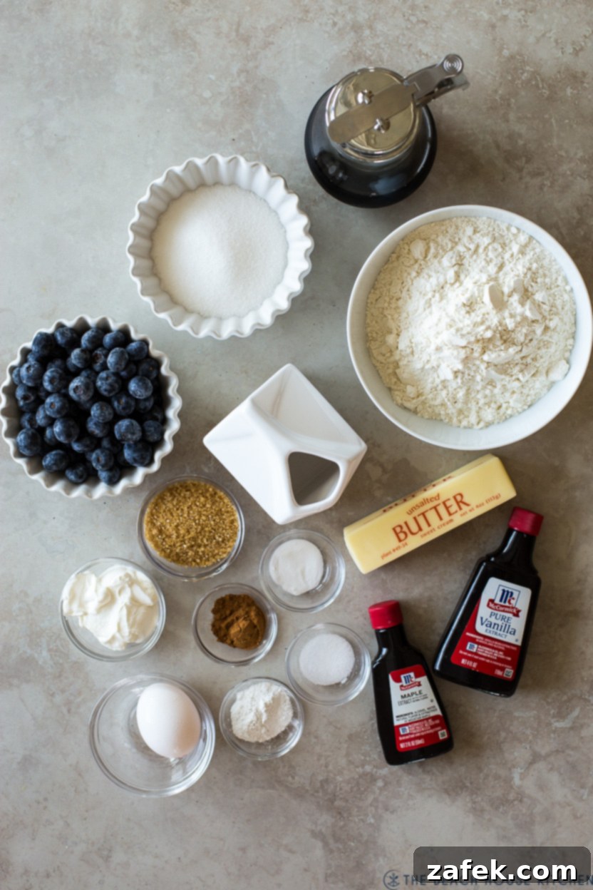 Sweet Maple Blueberry Pancake Muffins 4 Overhead flat lay photo showcasing all the fresh ingredients laid out for making Maple Blueberry Pancake Muffins, including flour, blueberries, butter, sugar, and extracts