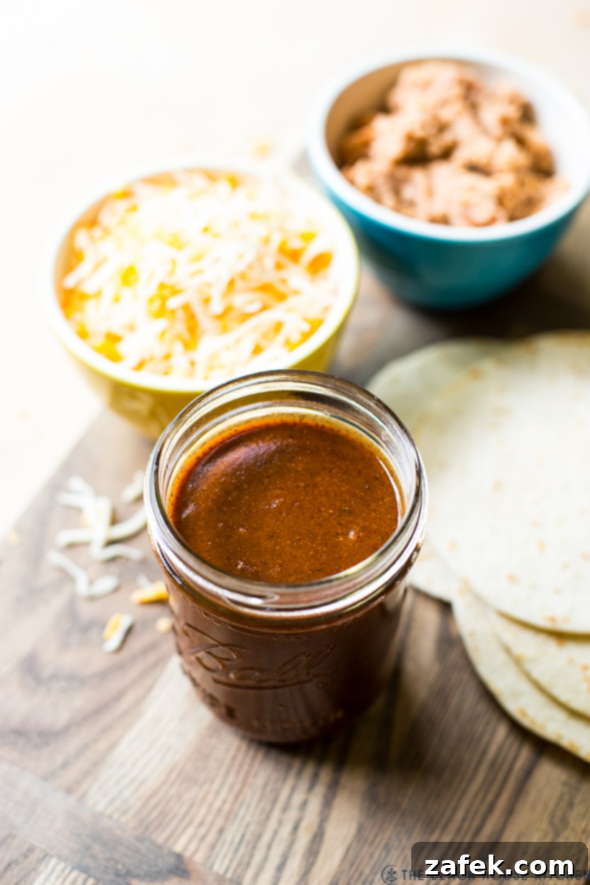 Close-up photo of a glass jar filled with rich, reddish-brown homemade enchilada sauce, ready for use.