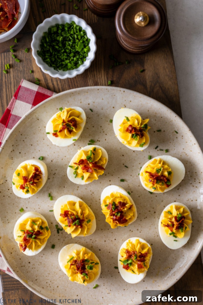 A beautifully arranged plate of Wasabi Deviled Eggs topped with crispy prosciutto pieces and a sprinkle of chives