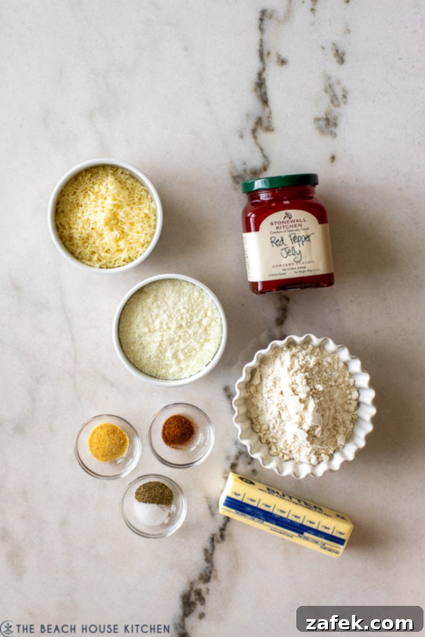 Overhead photo of all the fresh ingredients laid out for making cheesy thumbprints with red pepper jelly, including cheeses, butter, flour, and spices.