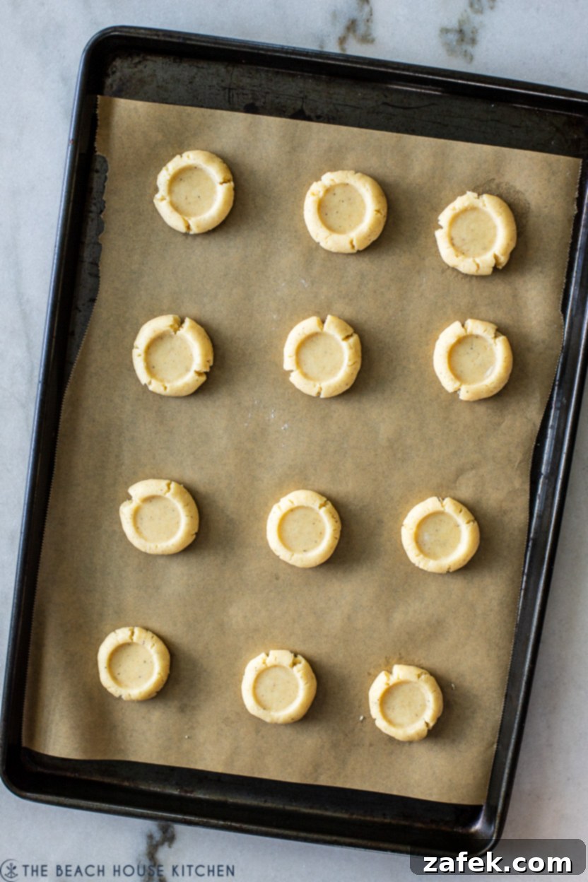 Overhead photo of a baking sheet with pre-baked thumbprints, neatly spaced and ready for chilling.