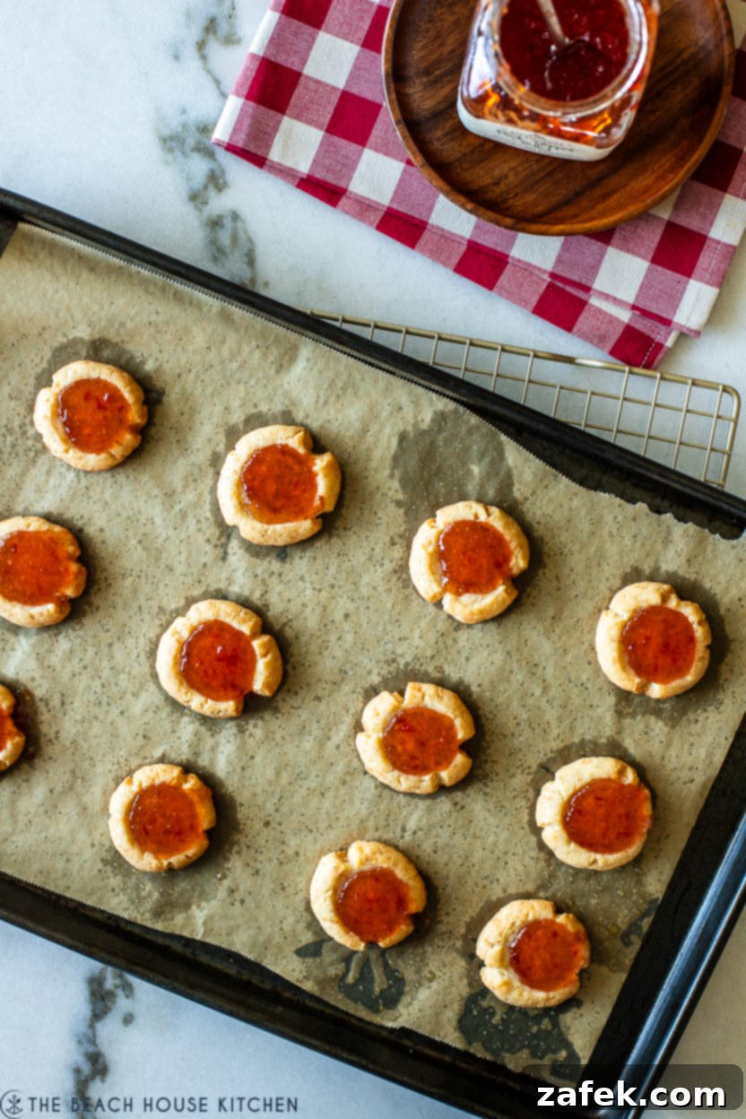 Overhead photo of a full tray of freshly baked cheesy thumbprints with red pepper jelly, golden and inviting.