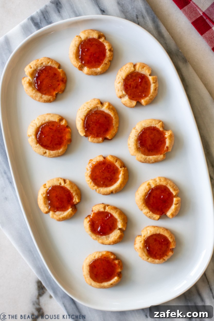 Up close overhead photo of a tray of cheesy thumbprints with red pepper jelly, showing the vibrant color and texture.