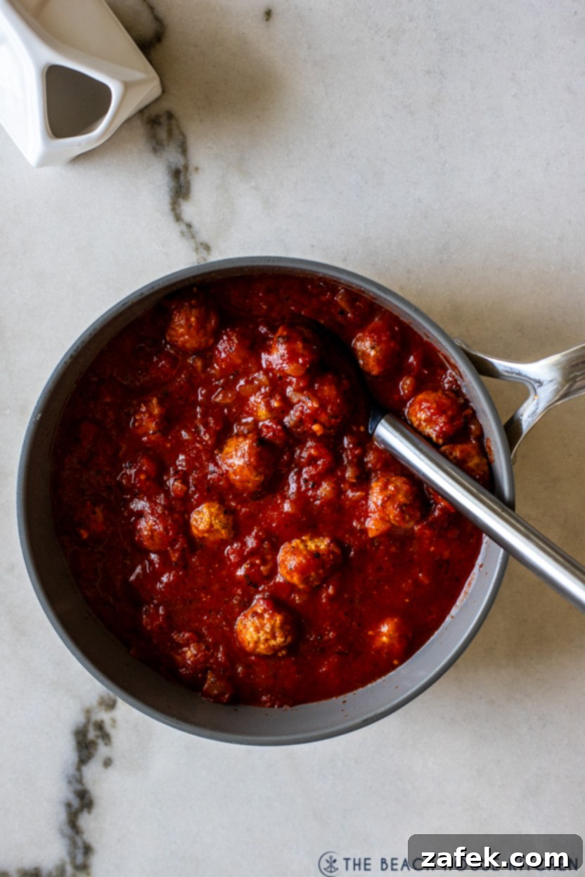 Frozen meatballs simmering in a vibrant crushed tomato sauce