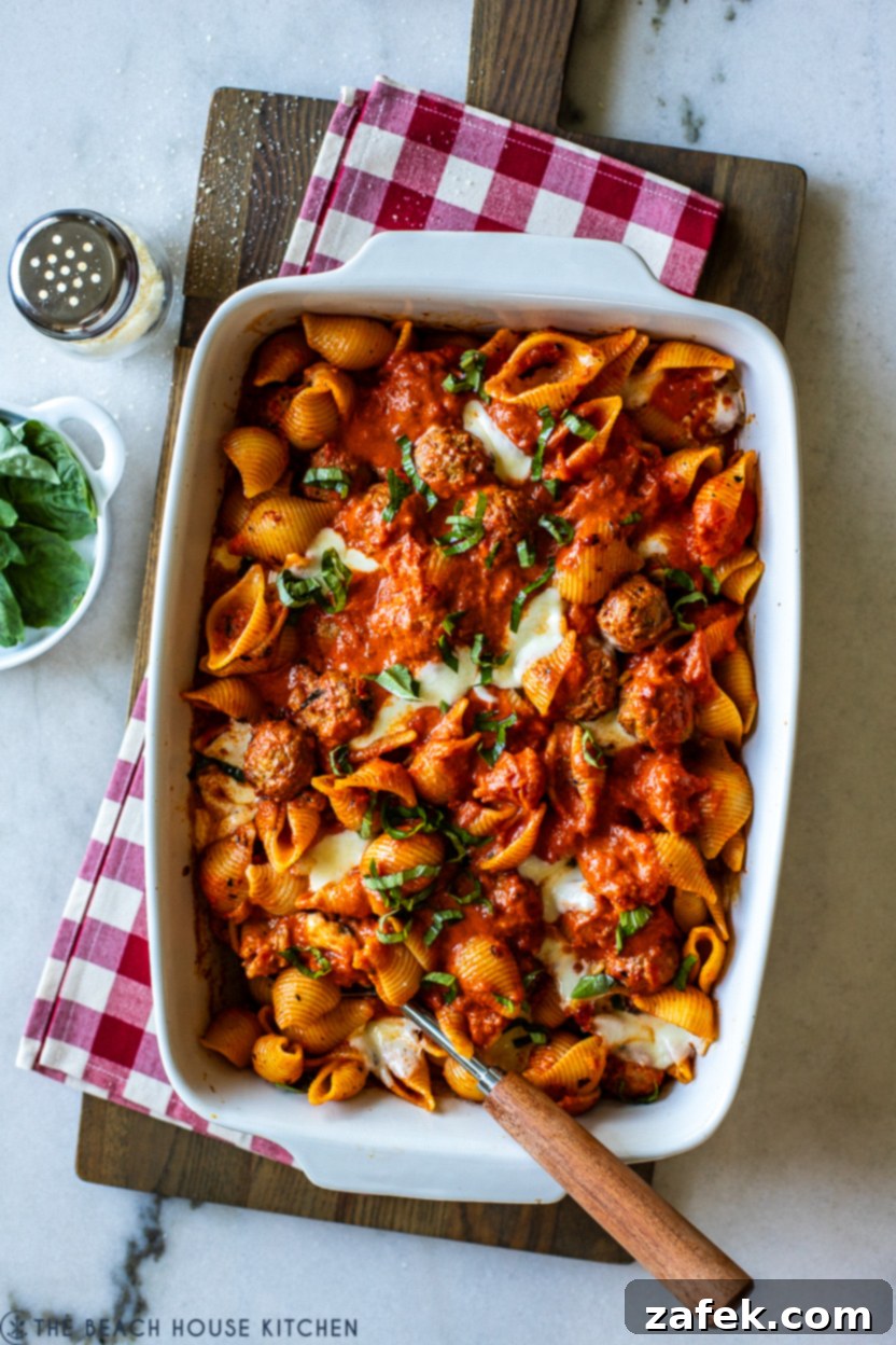 Close-up of a serving of Meatball Pasta Bake on a plate with fresh basil