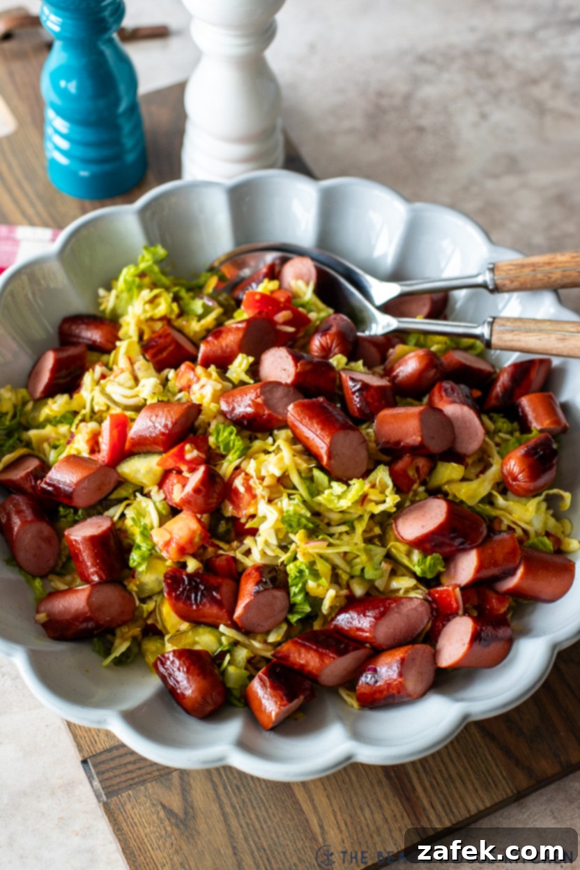 Up close photo of a single serving of Chicago Hot Dog Salad with perfectly sliced hot dogs on top, showcasing the vibrant colors and appealing texture of the salad ingredients.
