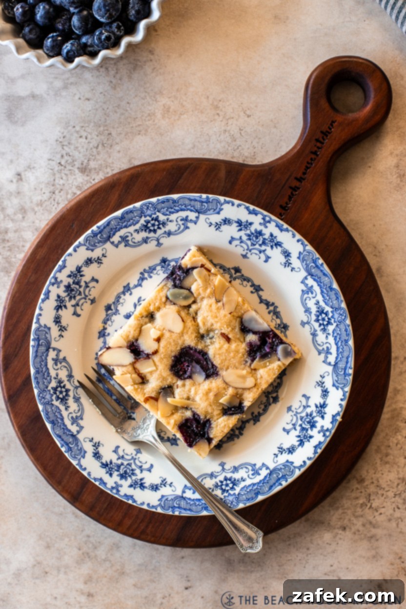 Overhead photo of a slice of a blueberry lemon blondie on a blue and white plate with a fork