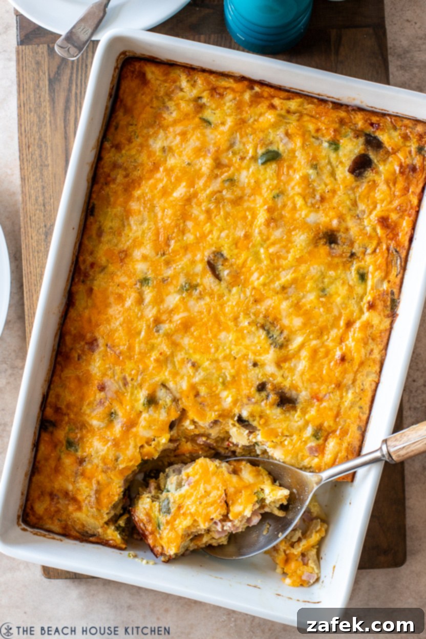 Golden Ham and Veggie Hash Brown Bake 2 Overhead photo of a white baking dish filled with a Ham and Vegetable Hash Brown Breakfast Casserole, garnished and ready to serve.