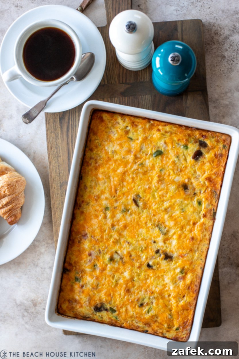 Golden Ham and Veggie Hash Brown Bake 3 Overhead photo of a breakfast casserole in a white baking dish, served with a cup of coffee and salt and pepper shakers, emphasizing a cozy morning meal.