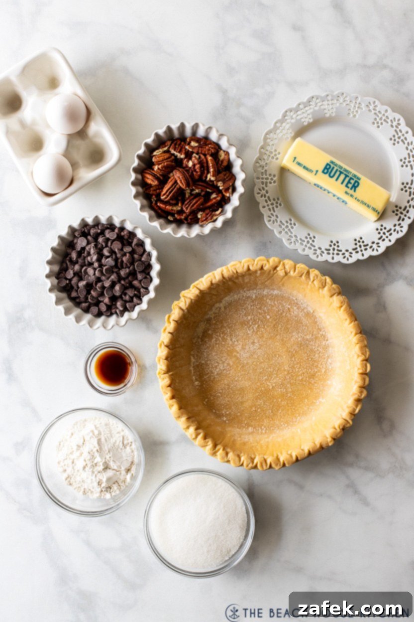 Ultimate Chocolate Chip Delight 3 Close-up overhead shot of all the simple ingredients laid out for an easy chocolate chip pie, including butter, sugar, flour, pecans, chocolate chips, eggs, vanilla, and a pie crust.