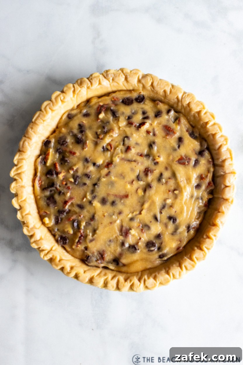 Ultimate Chocolate Chip Delight 7 Overhead photo of an unbaked chocolate chip pie filling poured into a frozen pie crust, ready for the oven.