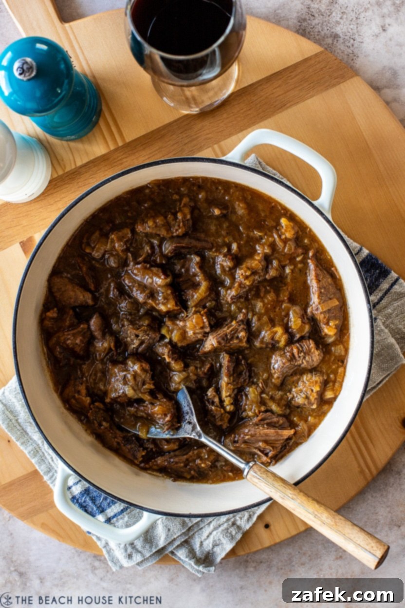 Overhead photo of a French onion pot roast in a Dutch oven, garnished and ready to be served, highlighting its rich, savory appeal