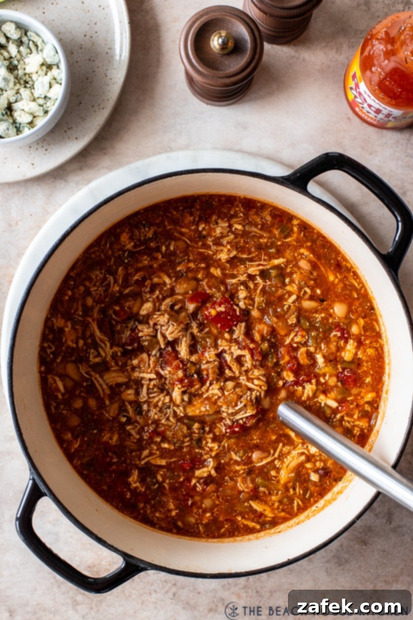 Overhead photo of a soup pot of buffalo chicken chili, garnished and ready to serve